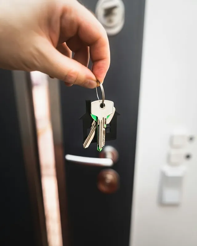 Hand holding a set of keys next to an open front door